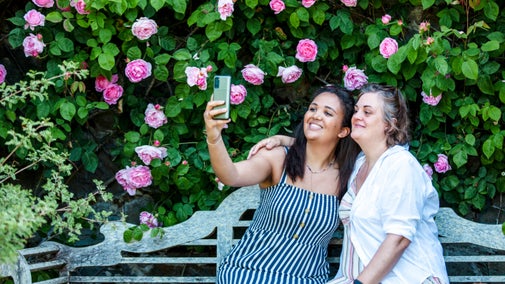 Visitors pose for a selfie in front of some roses in the Formal garden at Bodnant Garden, Conwy, Wales